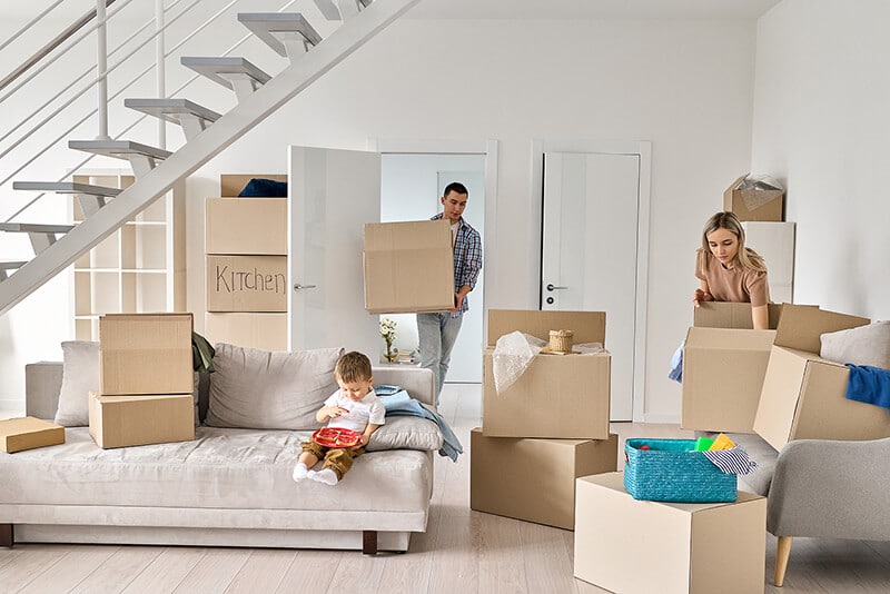 Young couple with a kid packing boxes on a moving day