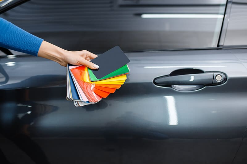 Vinyl wrapped car with male hand showing different color palettes Vinyl wrapped car with male hand showing different color palettes
