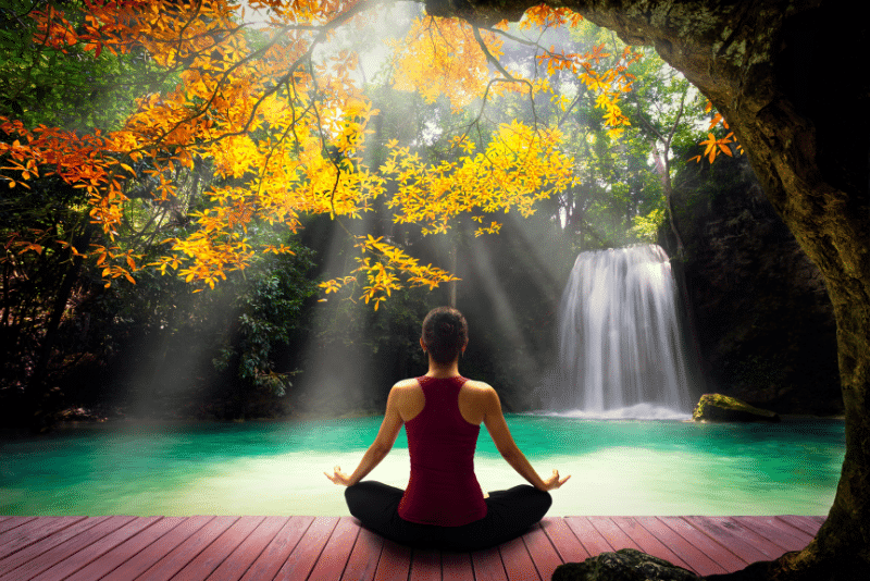 women meditating near waterfall women meditating near waterfall